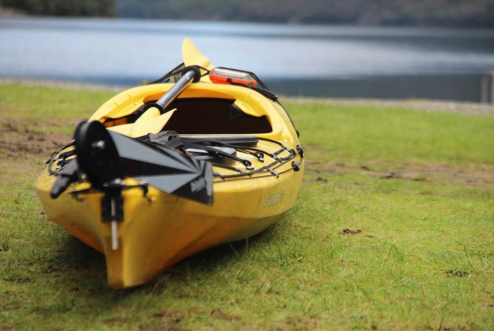 A yellow kayak resting on grassy ground near a lake, a peaceful choice for things to do in Homer Alaska.